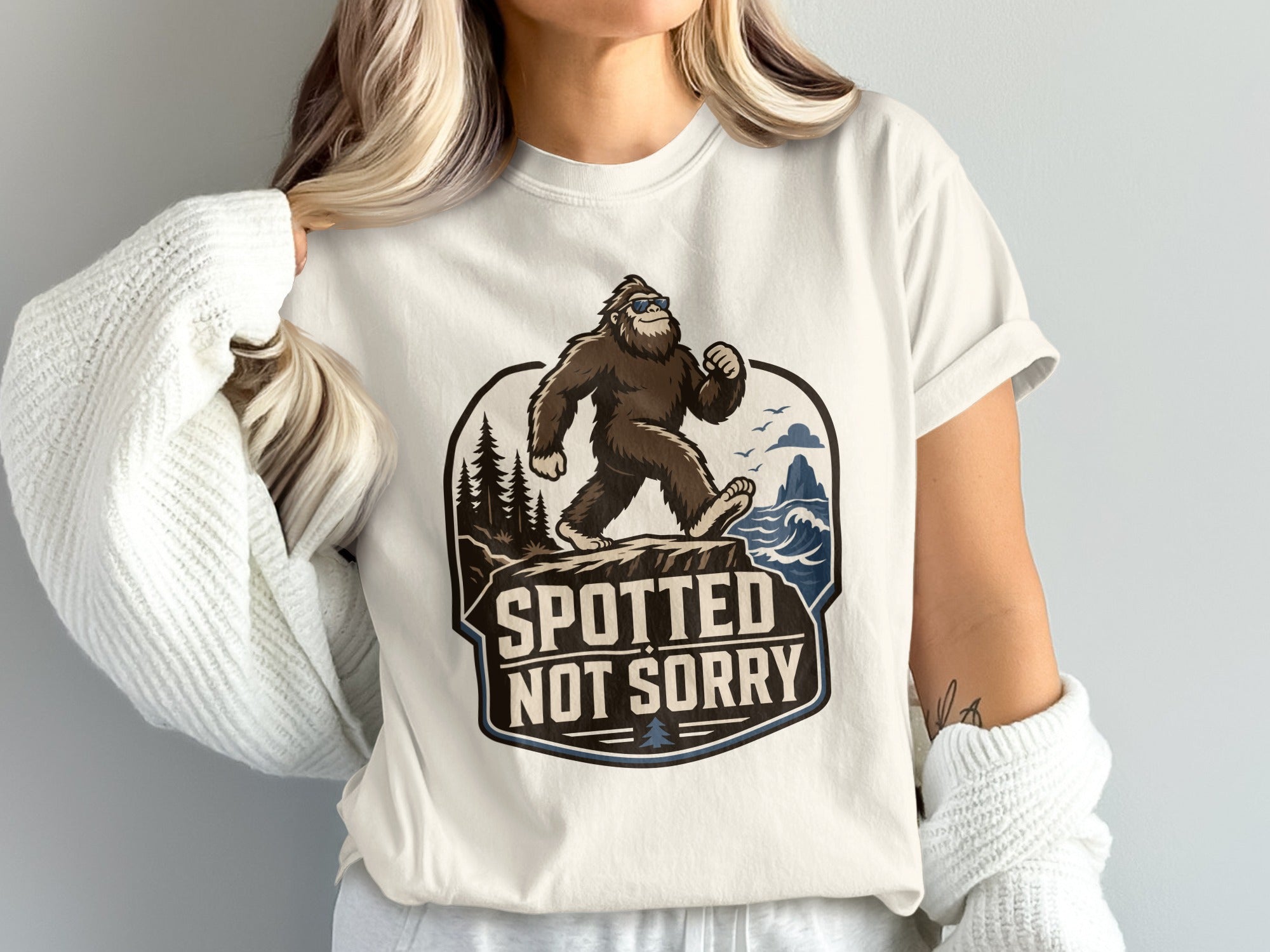Bigfoot wearing sunglasses walks on a cliff with "Spotted Not Sorry" text.