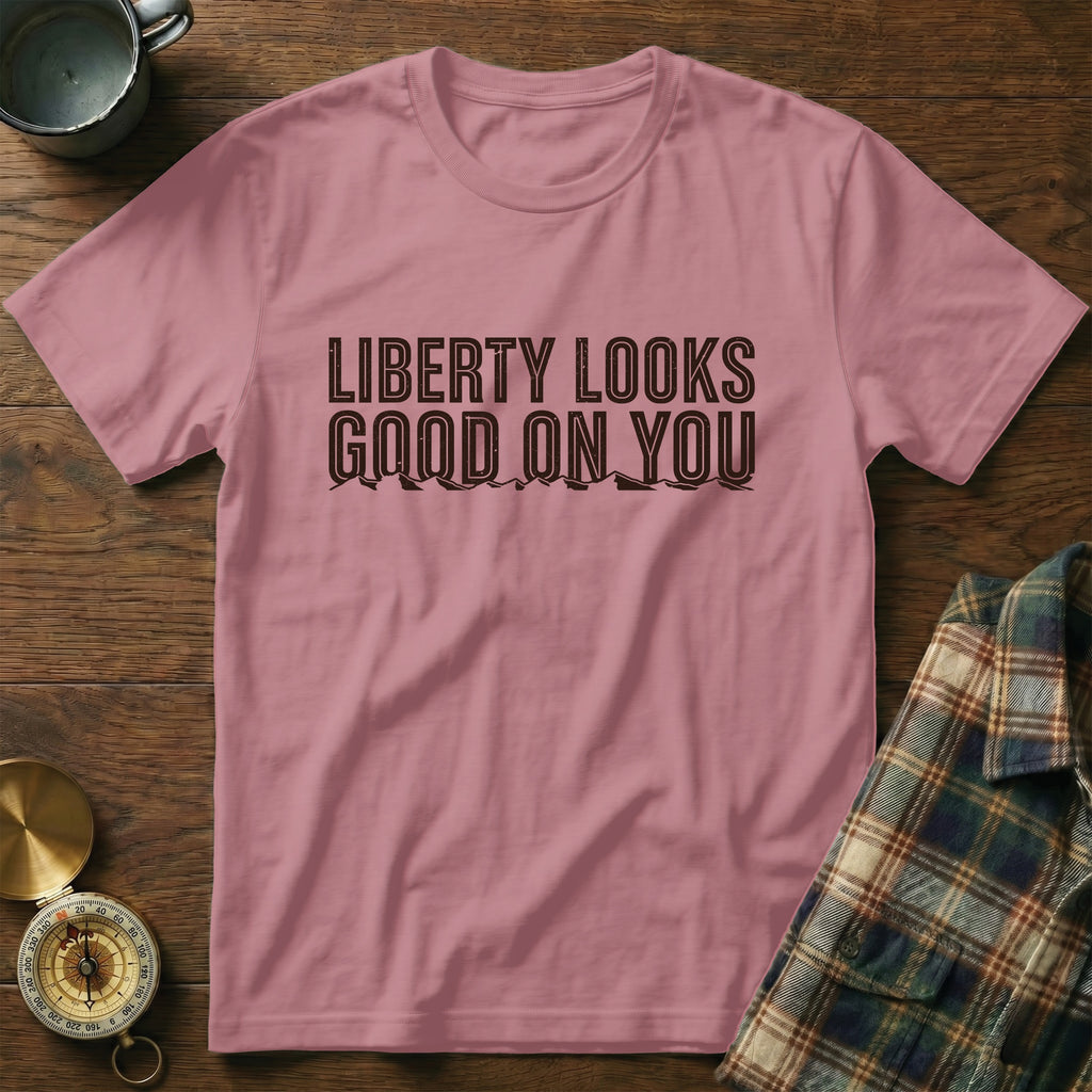 Pink t-shirt with "LIBERTY LOOKS GOOD ON YOU" graphic and mountain outline.