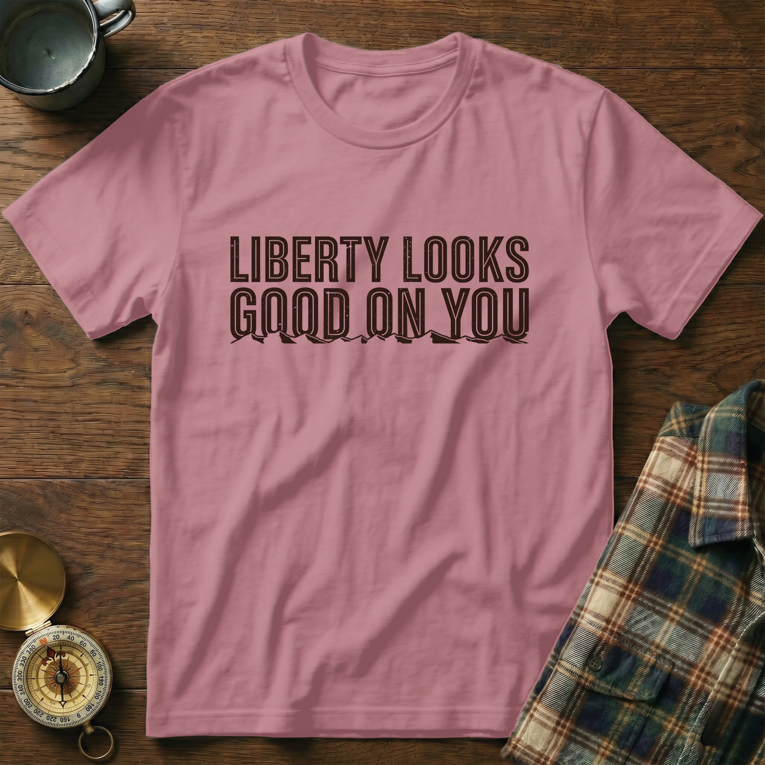 Pink t-shirt with "LIBERTY LOOKS GOOD ON YOU" graphic and mountain outline.