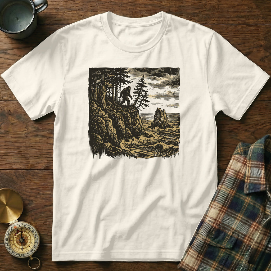 White t-shirt with Bigfoot on a cliff overlooking the ocean.