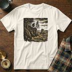 White t-shirt with Bigfoot on a cliff overlooking the ocean.
