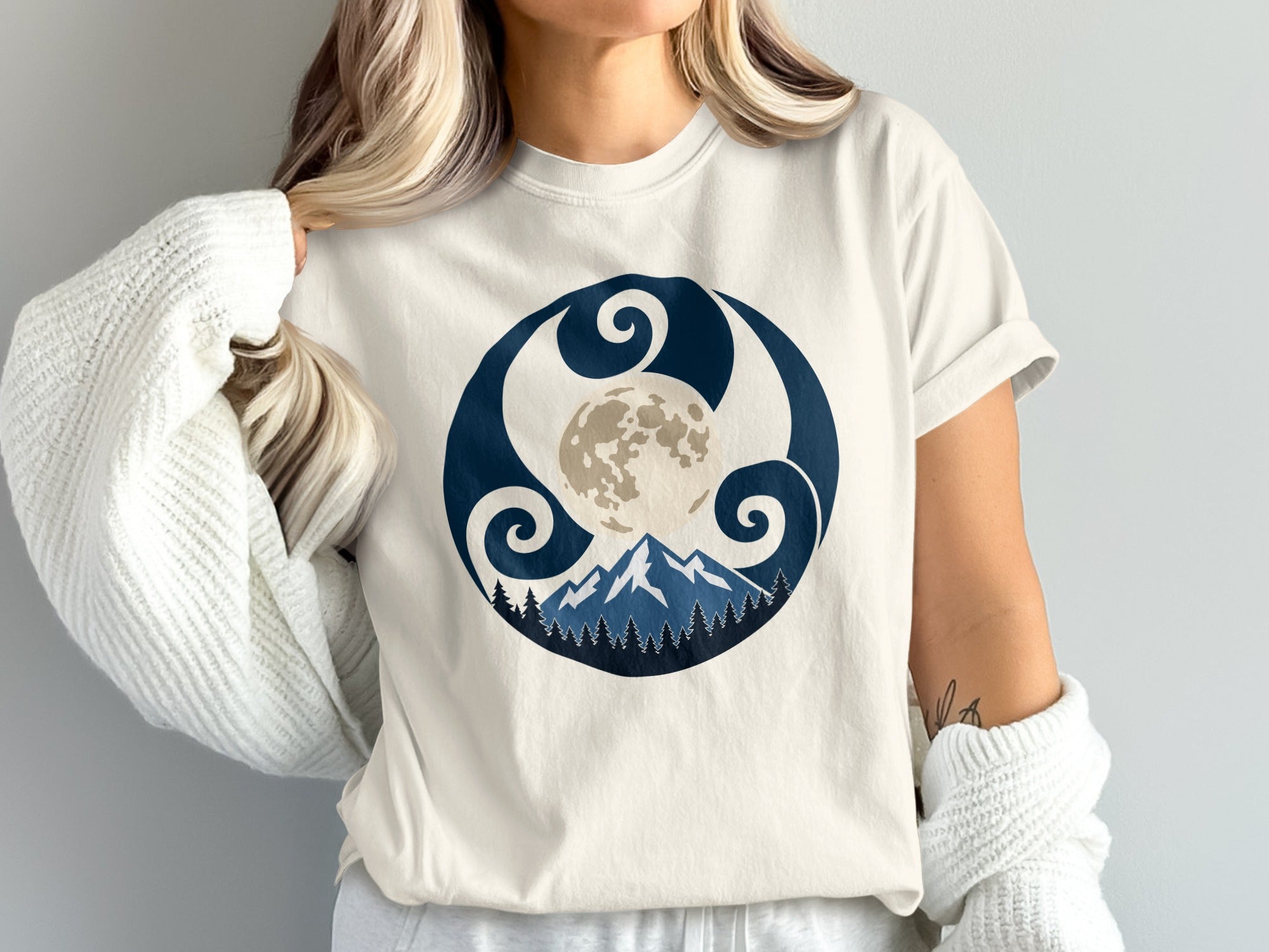 Cream shirt with a dark blue circular graphic of a moon, mountains, and trees.