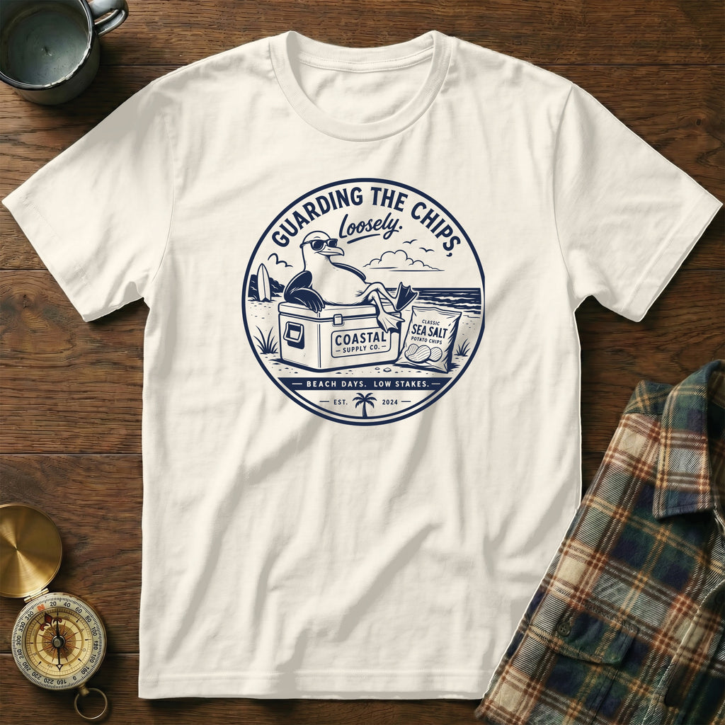 White t-shirt with blue graphic of seagull "Guarding The Chips" with cooler and chips.