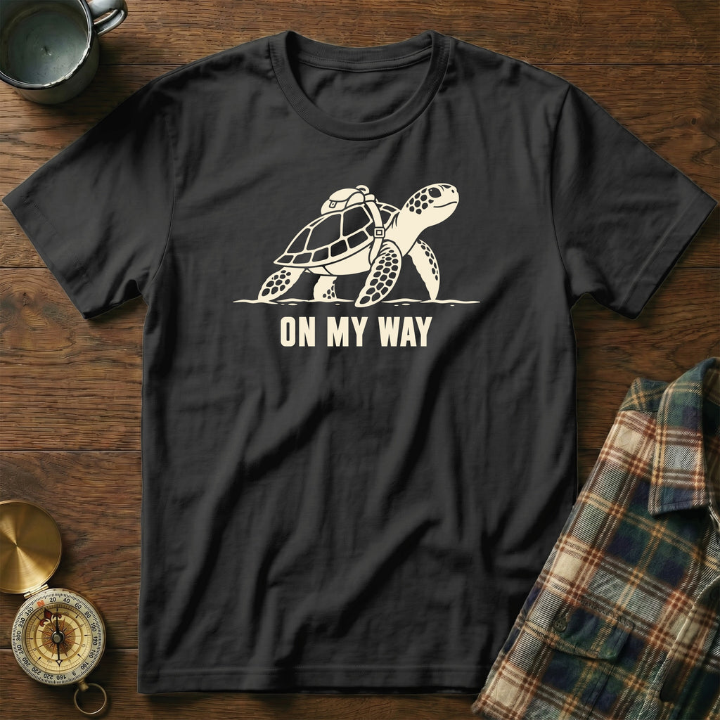 Black t-shirt with graphic of turtle with backpack and text "ON MY WAY".