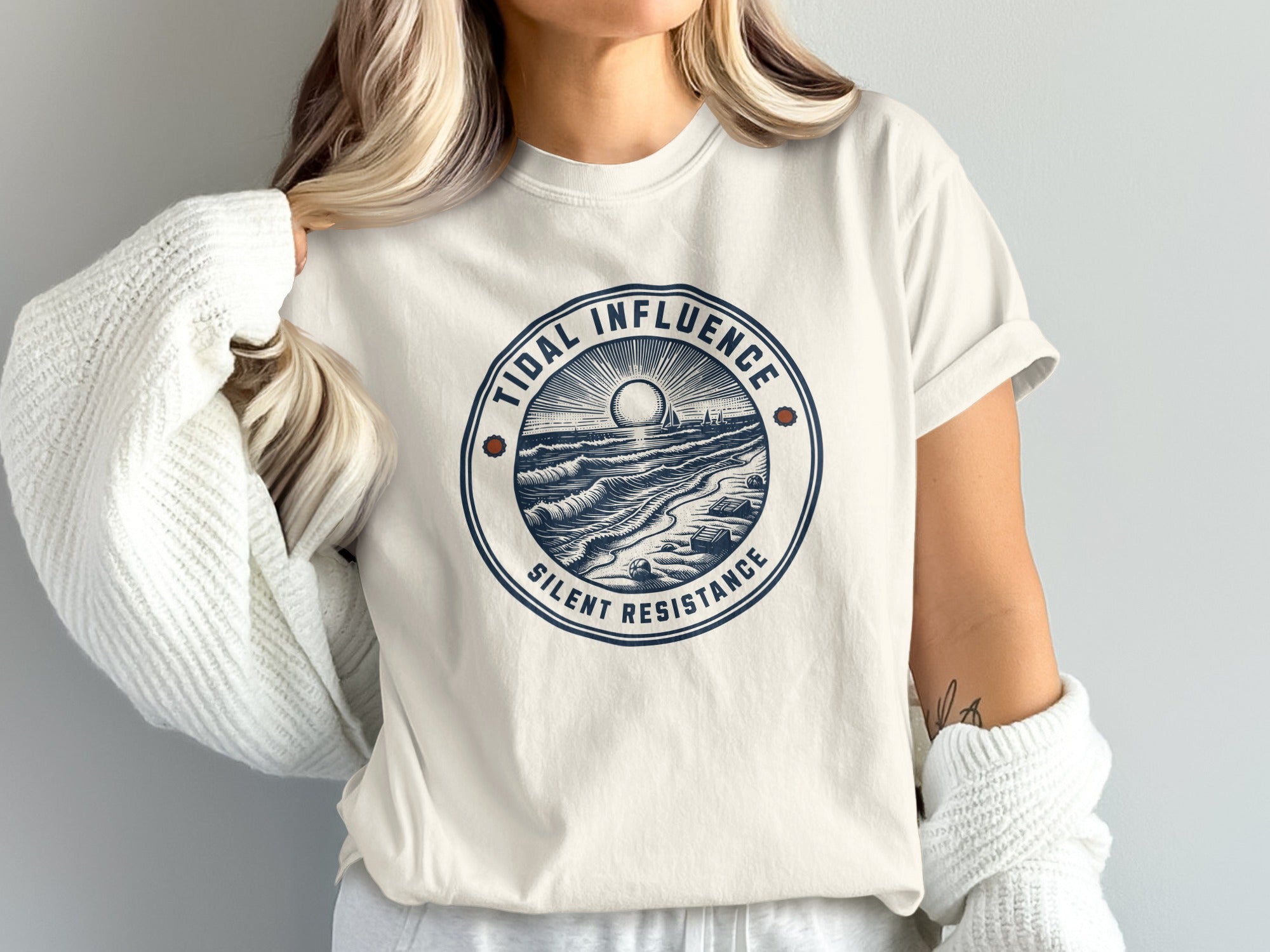 Cream t-shirt with circular "Tidal Influence Silent Resistance" graphic of waves and sun.