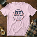Pink t-shirt with "LIBERTY LOOKS GOOD ON YOU" text and mountain graphic.