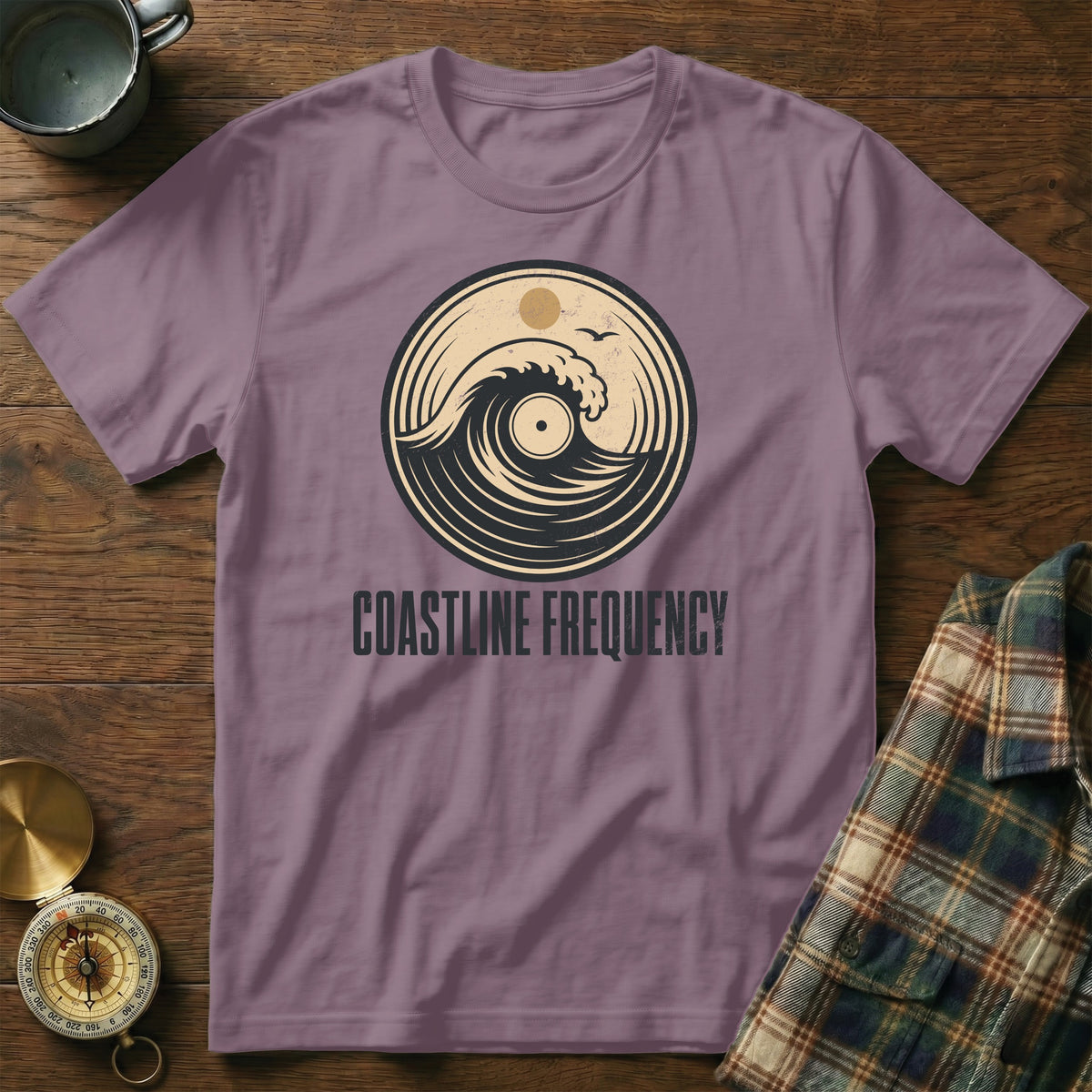 Purple t-shirt with "Coastline Frequency" and a wave in a vinyl record design.