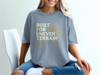 Light blue t-shirt with "Built for Uneven Terrain" and mountain graphic.