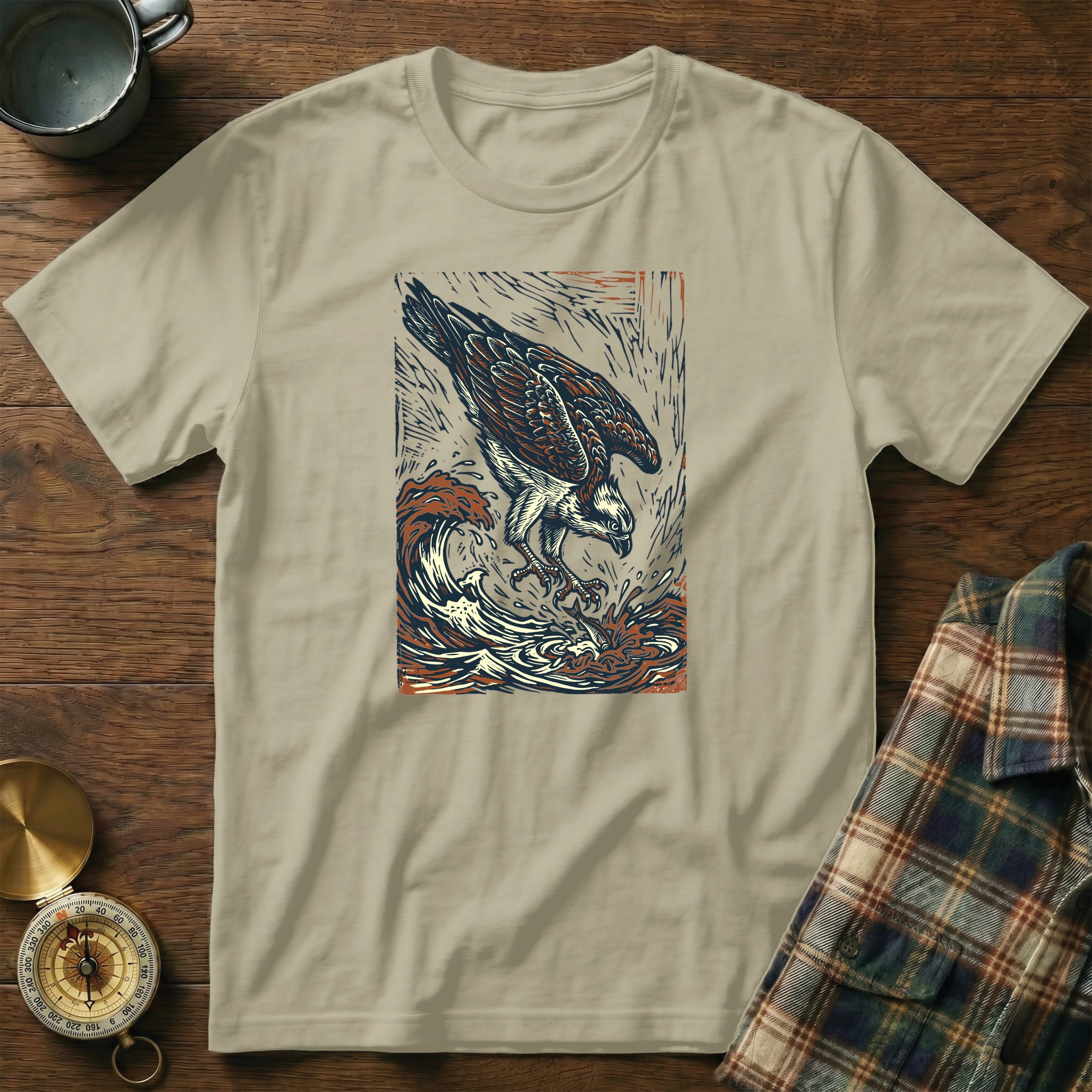 Osprey diving into waves, vintage artistic illustration on tan t-shirt.