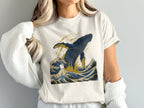 T-shirt with a jumping blue whale and crashing waves in blue and gold.