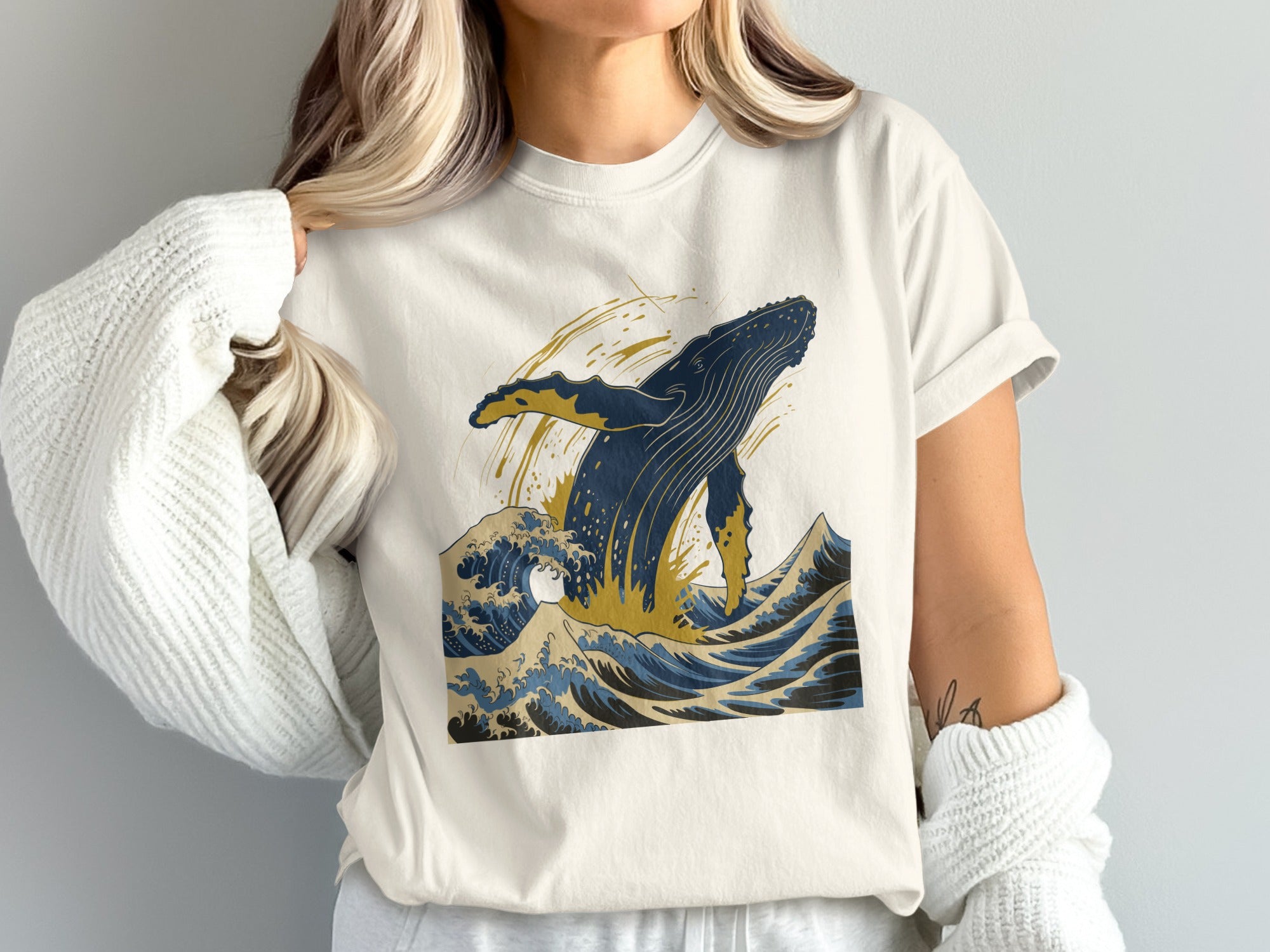 T-shirt with a jumping blue whale and crashing waves in blue and gold.