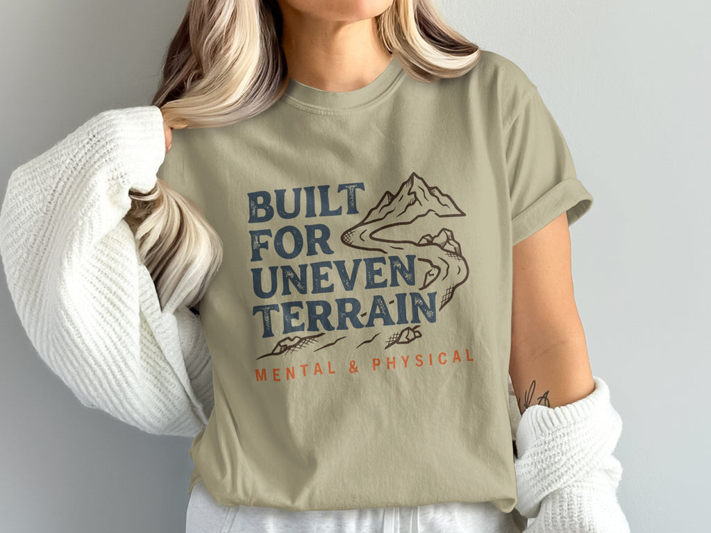 T-shirt with "Built for Uneven Terrain" text and mountain graphic.