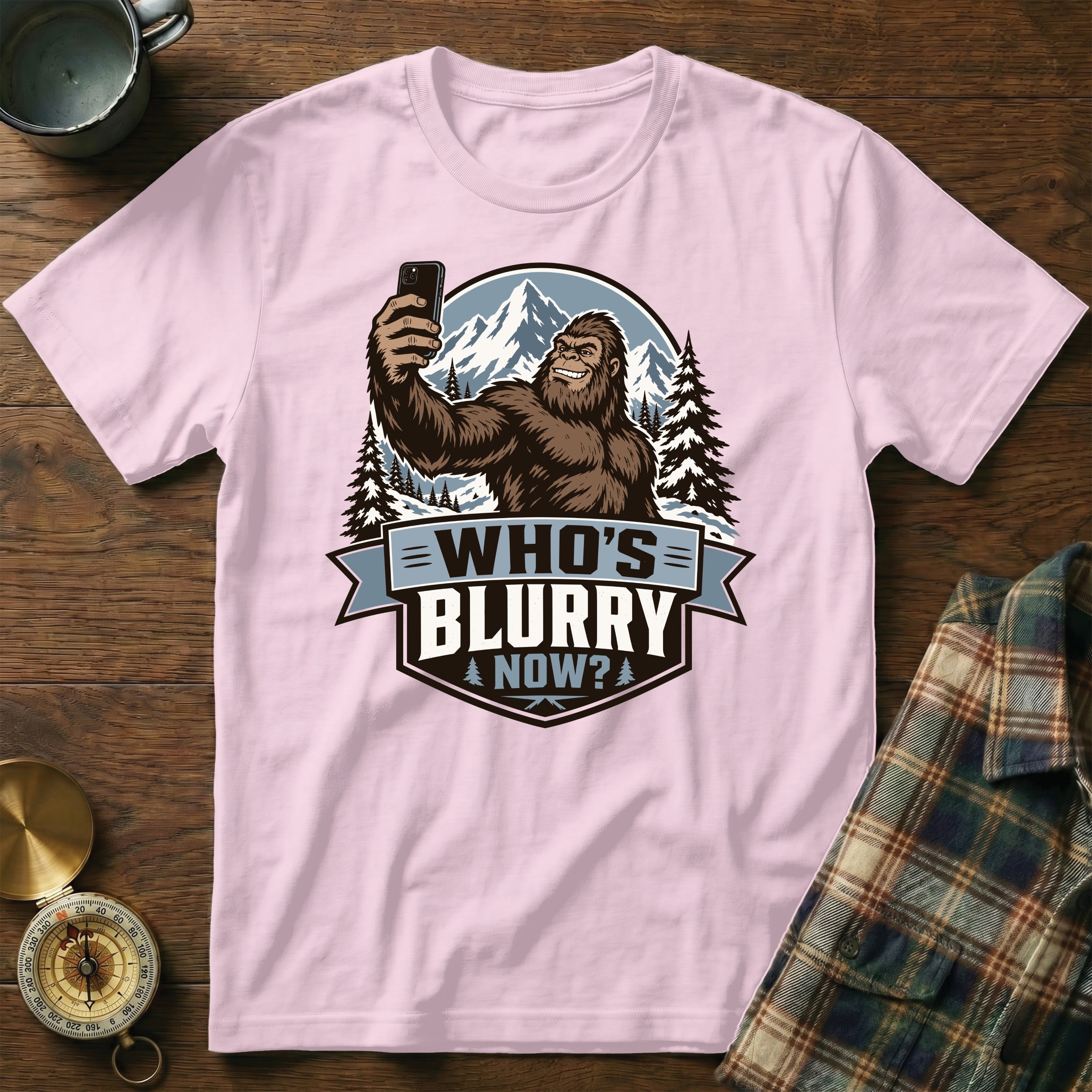 Bigfoot taking a selfie in mountains with text "Who's Blurry Now?".