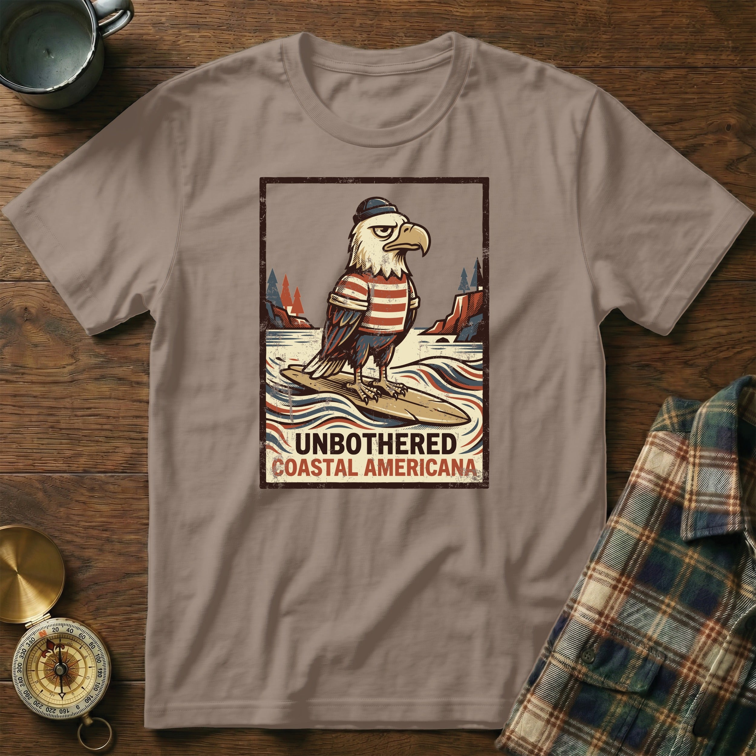 T-shirt with illustration of an eagle surfing and text "UNBOTHERED COASTAL AMERICANA".