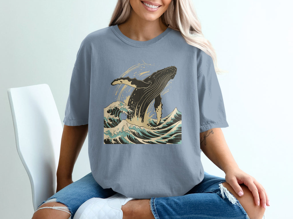 Blue t-shirt with a graphic of a whale breaching in ocean waves.