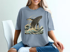 Blue t-shirt with a graphic of a whale breaching in ocean waves.