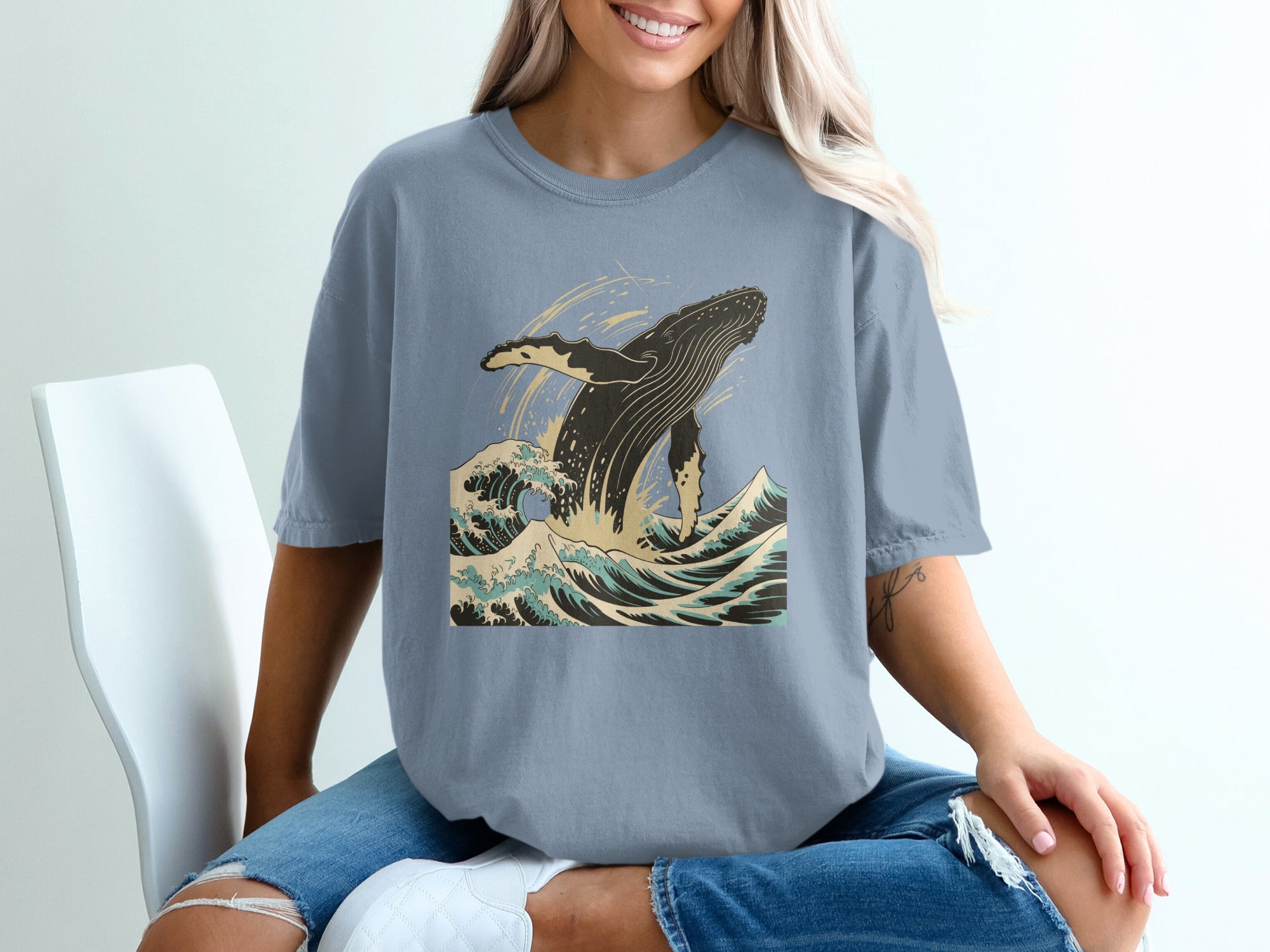 Blue t-shirt with a graphic of a whale breaching in ocean waves.