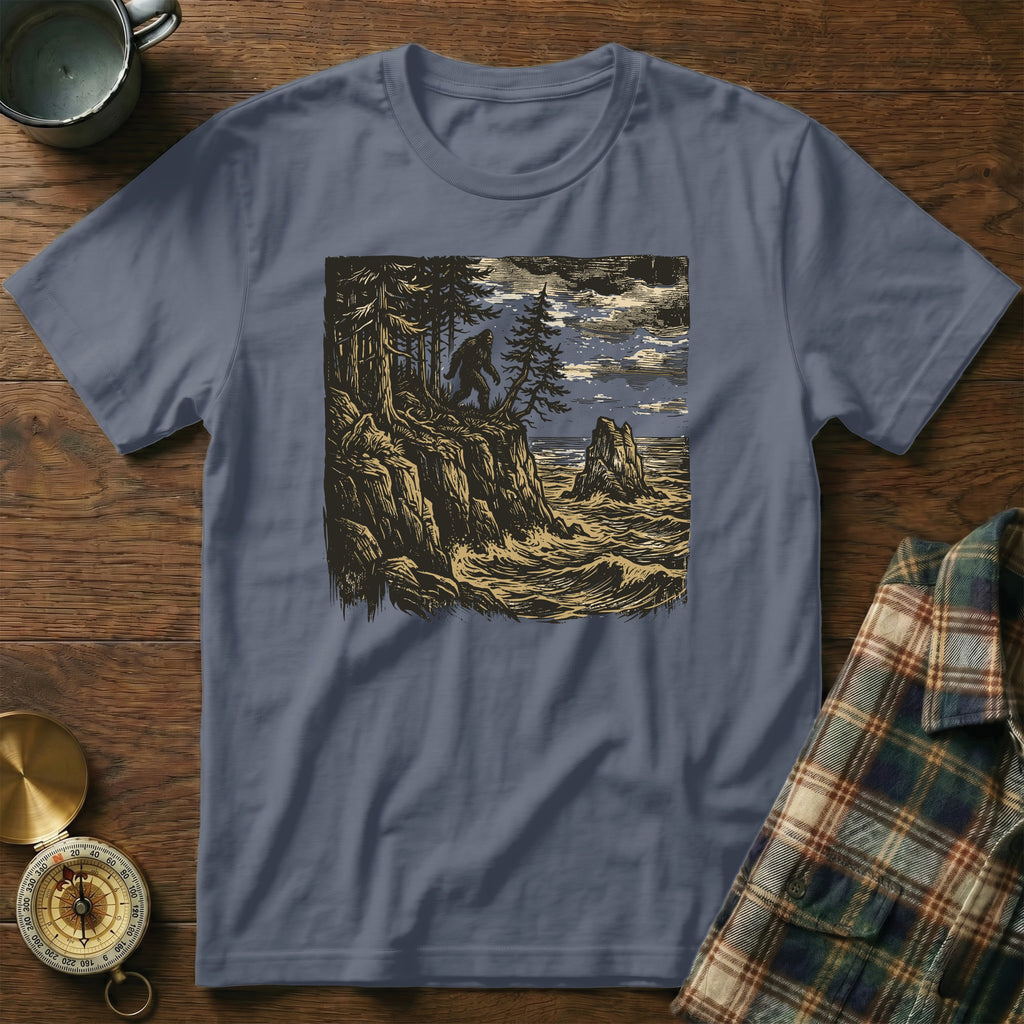 Woodcut style t-shirt design featuring Bigfoot on a rocky cliff overlooking waves.