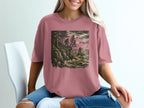 Bigfoot silhouetted on a rocky coast with crashing waves and trees.
