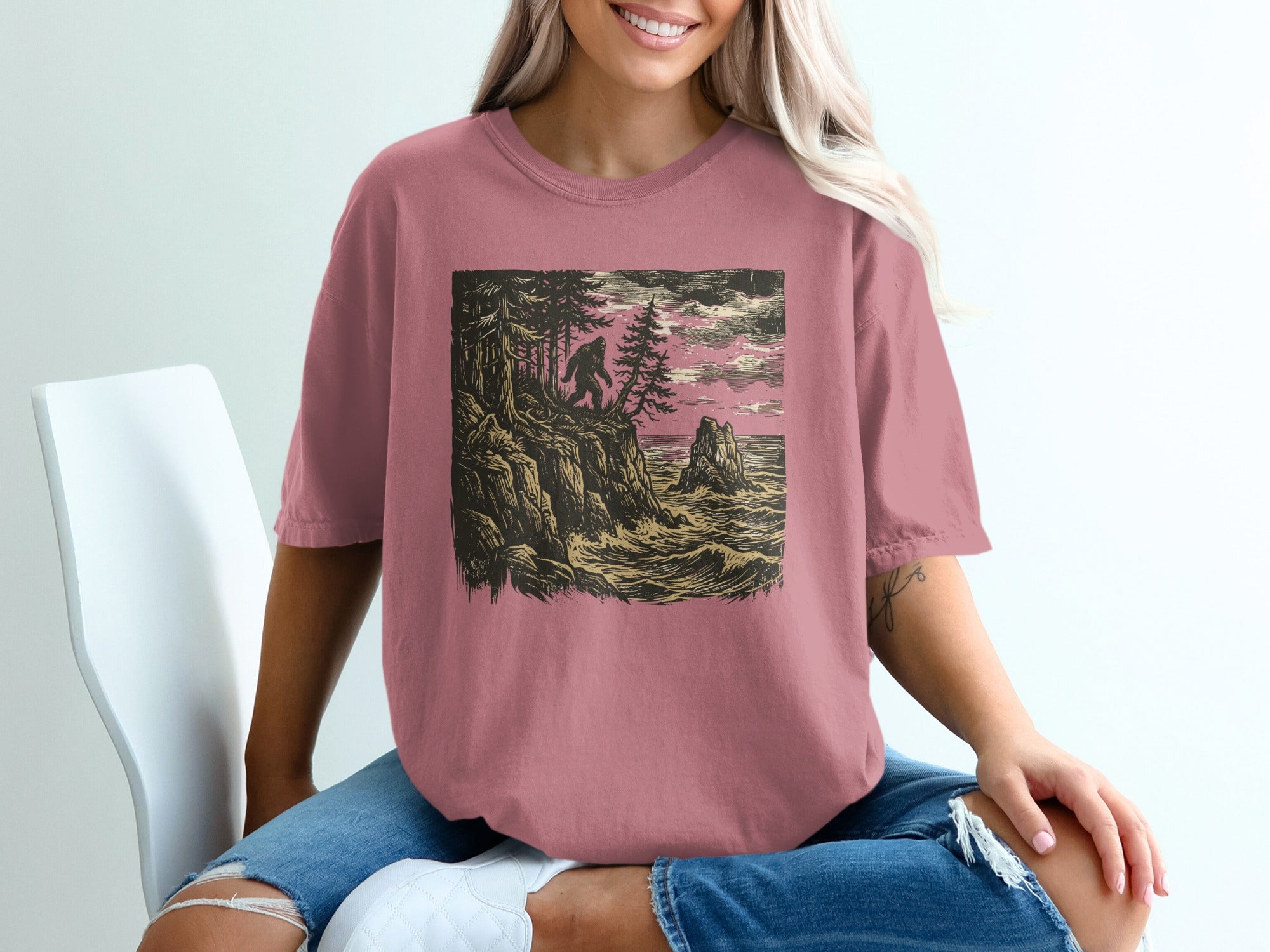 Bigfoot silhouetted on a rocky coast with crashing waves and trees.
