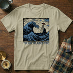 T-shirt with "The Unexplained Tide" text and a wave with a UFO and lighthouse.