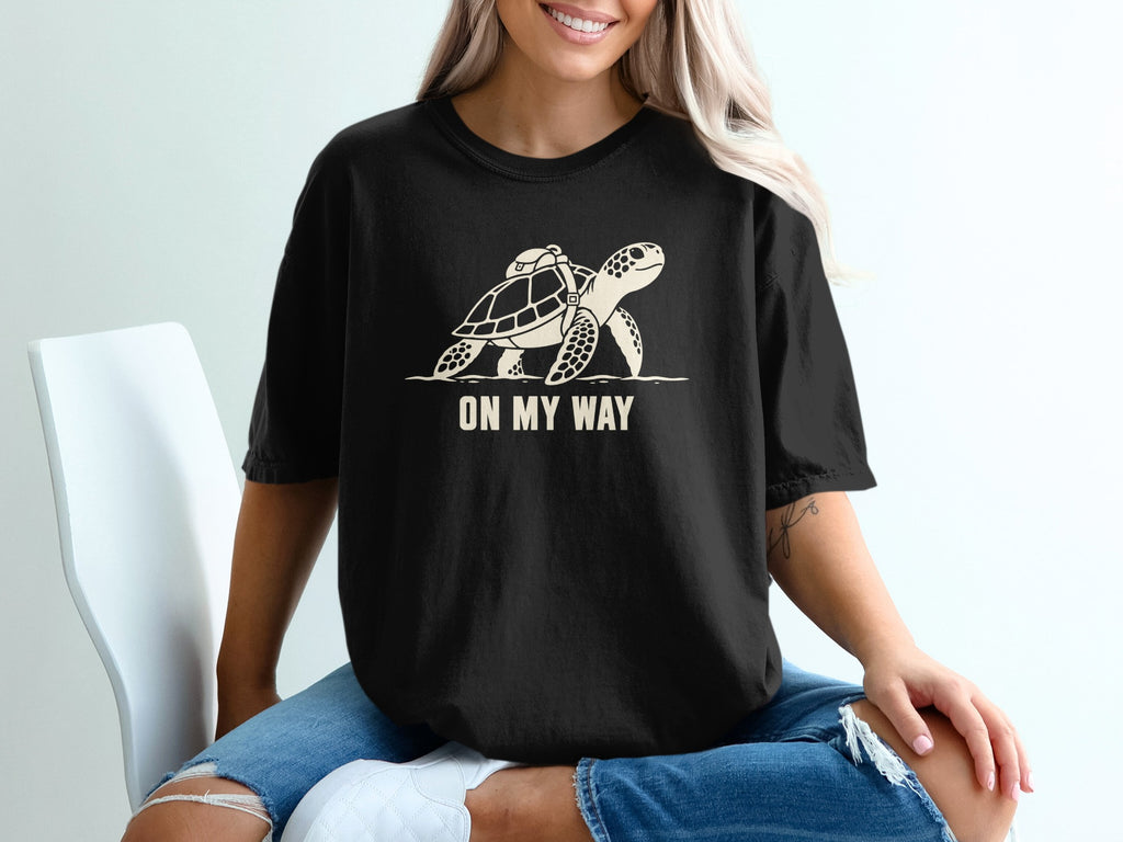 Black t-shirt with graphic of a turtle with a backpack and text "ON MY WAY".