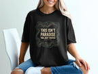 Black t-shirt with "This Isn't Paradise, You Just Visited. We Stayed." text.