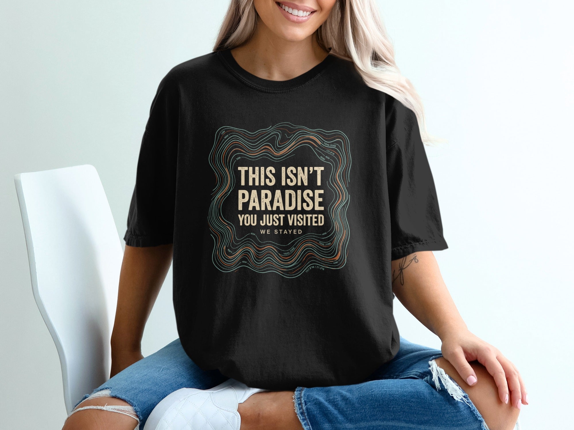 Black t-shirt with "This Isn't Paradise, You Just Visited. We Stayed." text.