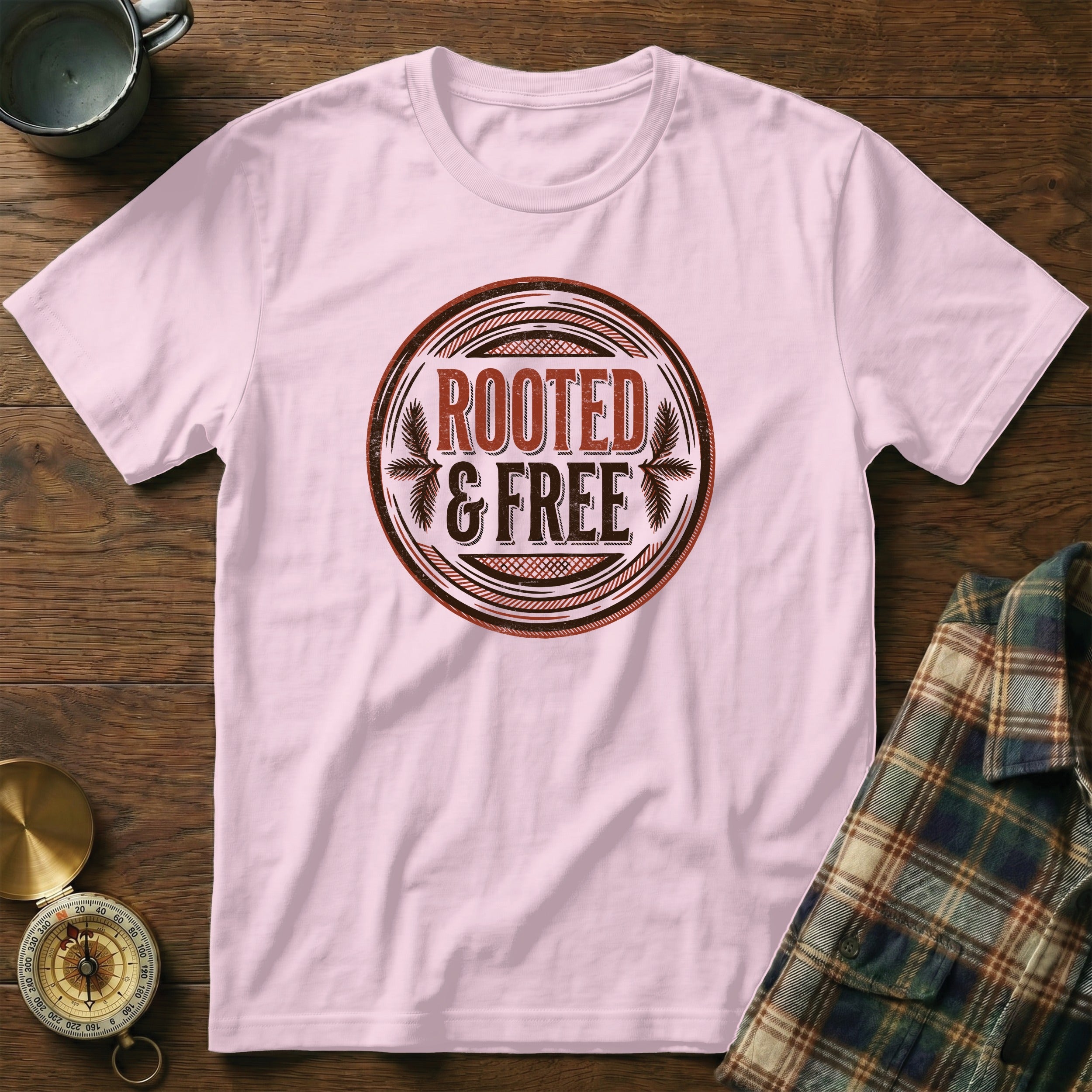 Pink t-shirt with circular "ROOTED & FREE" graphic.