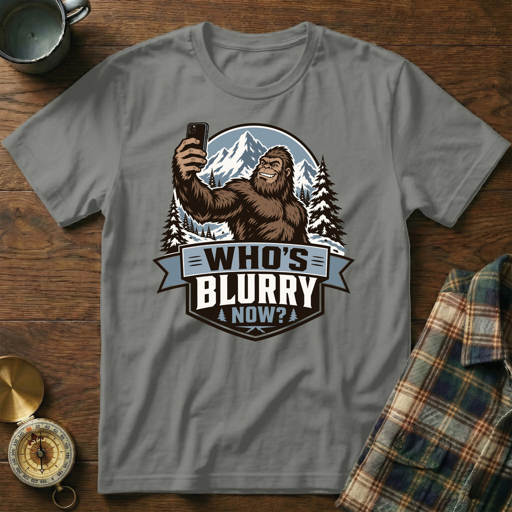 Bigfoot taking a selfie in the mountains with the text "Who's Blurry Now?".