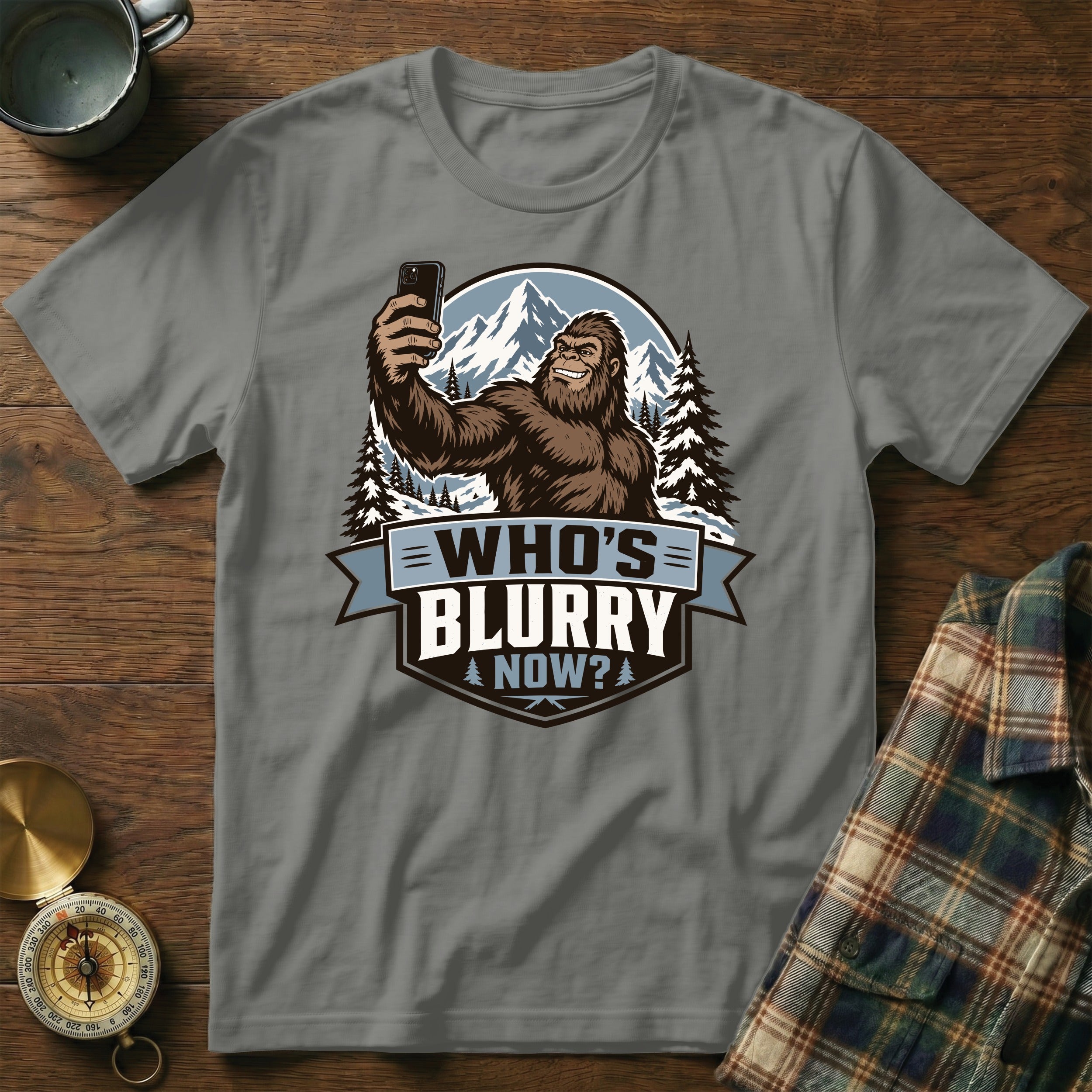Bigfoot taking a selfie in the mountains with the text "Who's Blurry Now?".