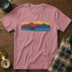Pink t-shirt with a mountain and lake graphic featuring a person in a canoe.