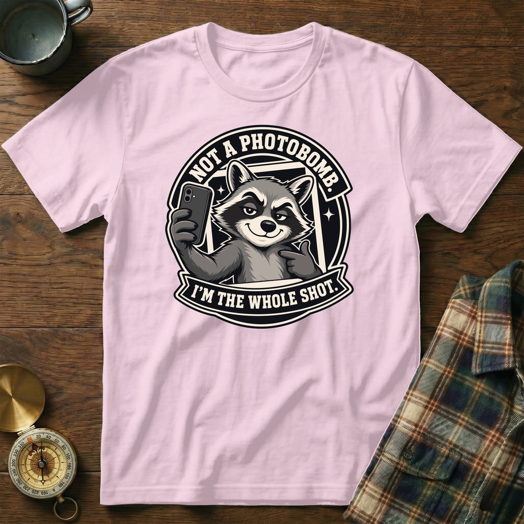 Pink t-shirt with a graphic of a raccoon taking a selfie and text saying "NOT A PHOTOBOMB."