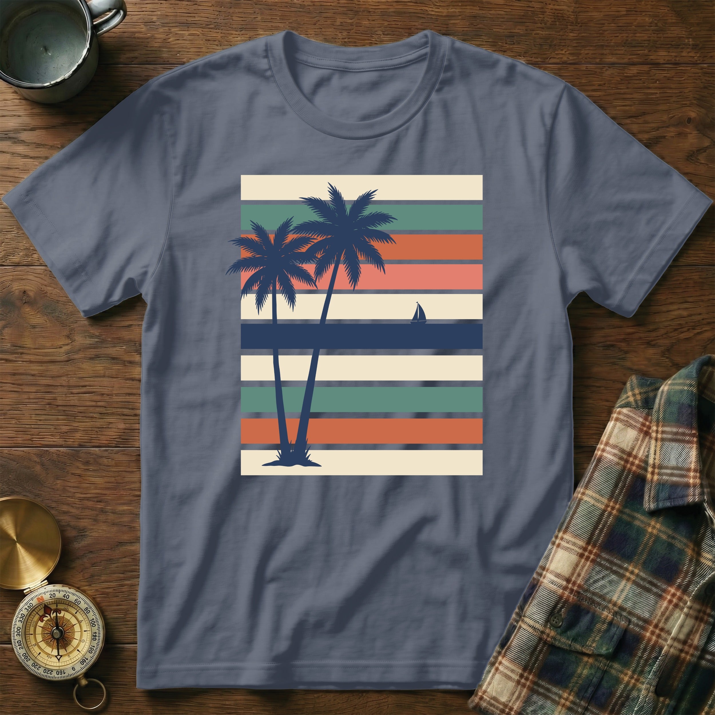 T-shirt with two palm trees and sailboat on striped background.