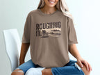 Brown t-shirt with "ROUGHING IT." text and a beach scene graphic.