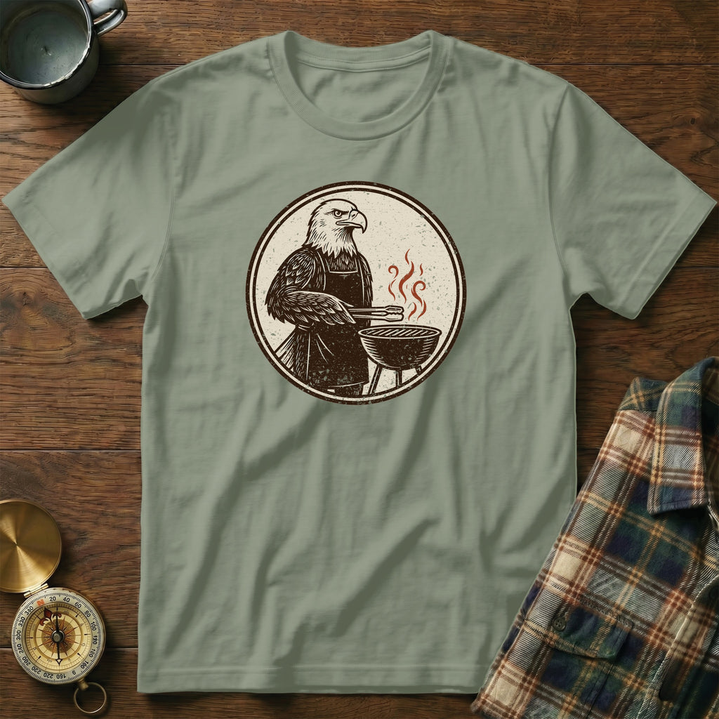 Bald eagle wearing an apron grills outdoors with tongs and a red-tinged grill.