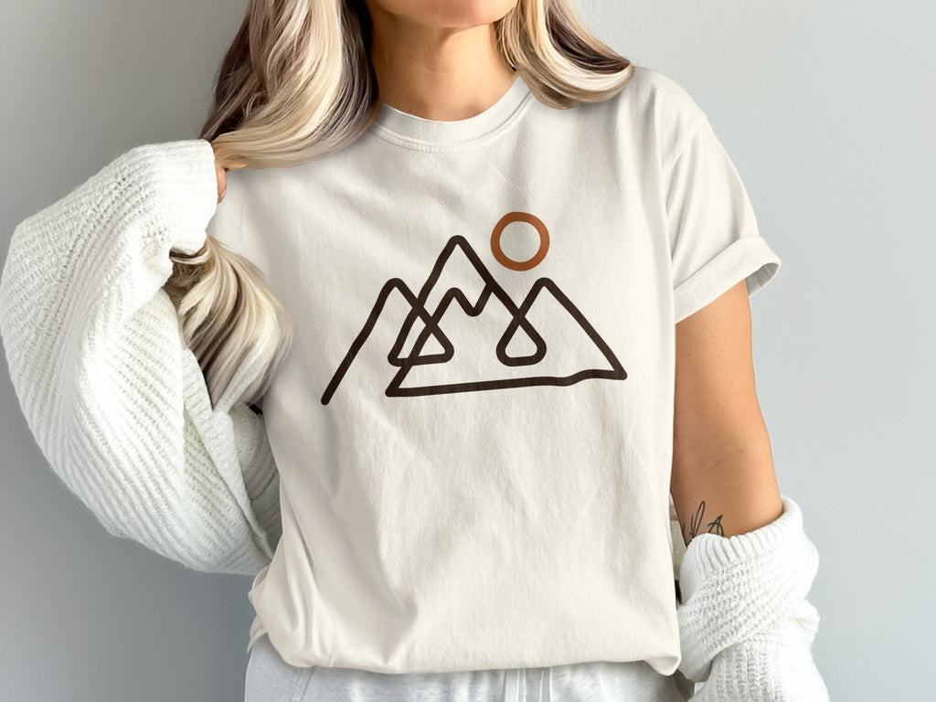 Cream t-shirt with abstract mountain range and sun graphic.