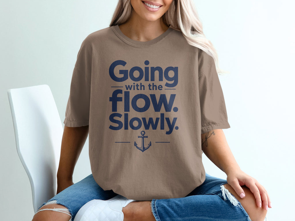 A person wearing a brown t-shirt featuring the blue text Going with the flow. Slowly. and an anchor graphic.