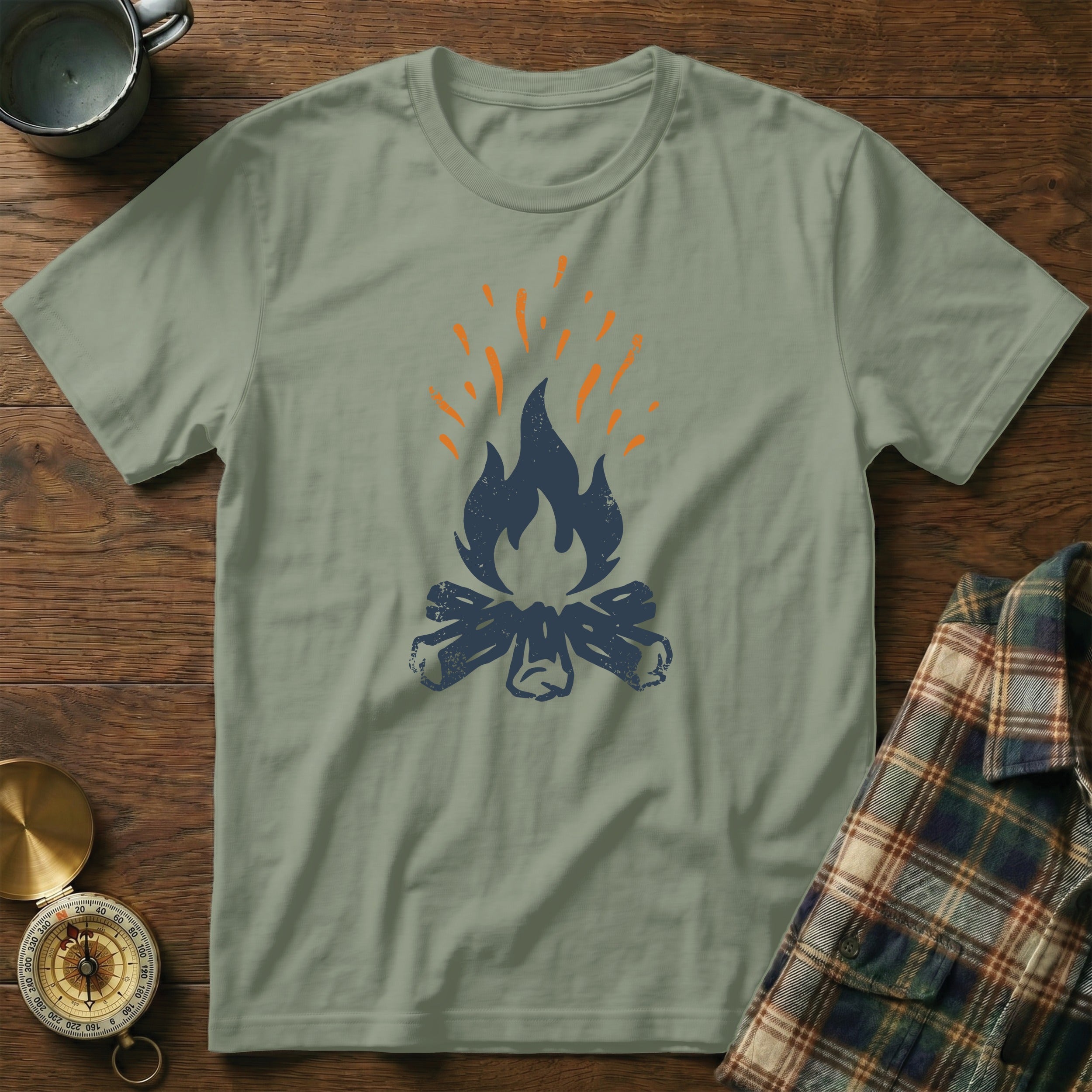 Gray t-shirt with a blue and orange campfire graphic on a wooden surface.