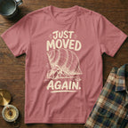 Pink t-shirt with a sketch of a hermit crab and text "JUST MOVED AGAIN."