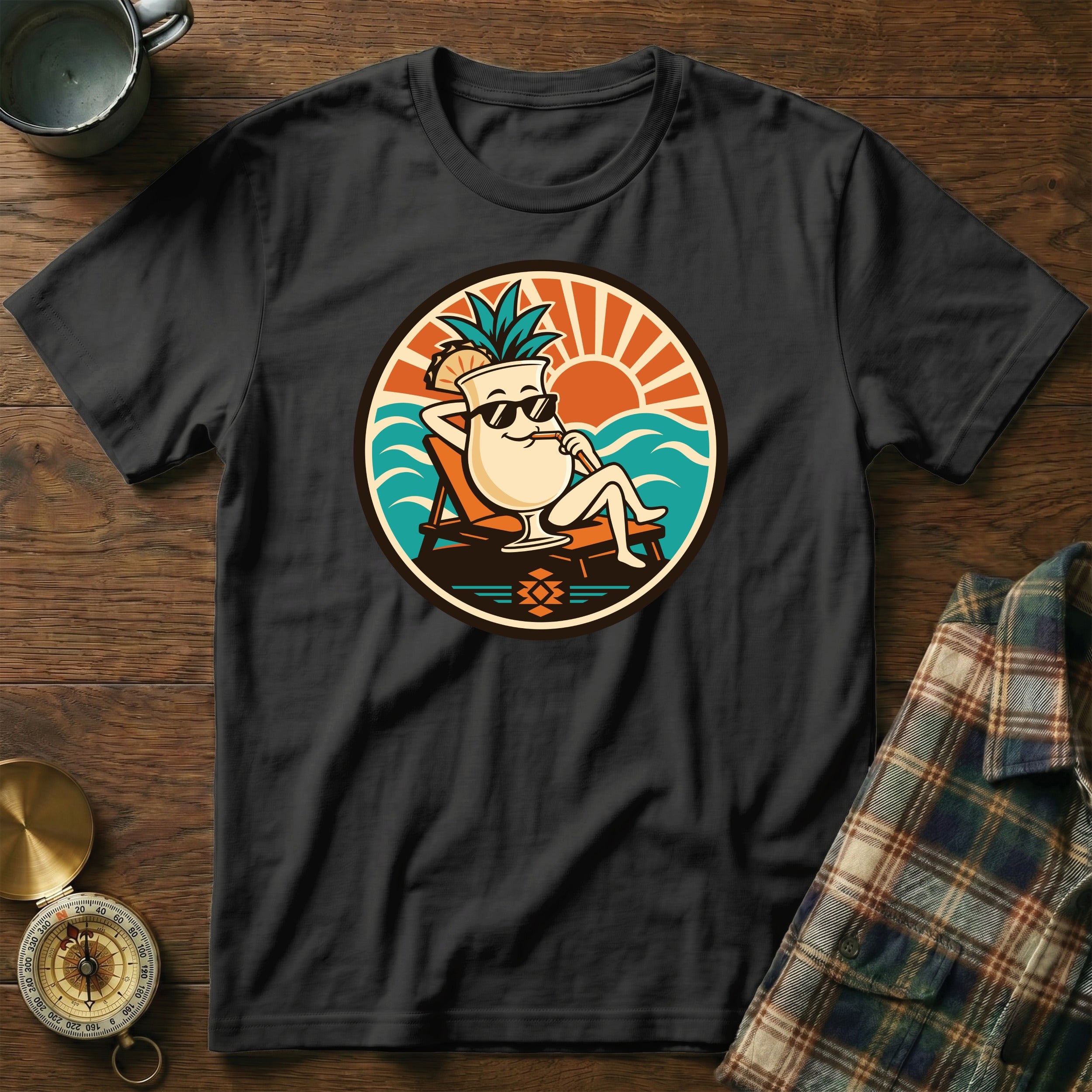 Black t-shirt with cartoon cocktail relaxing on a deck chair near the ocean.