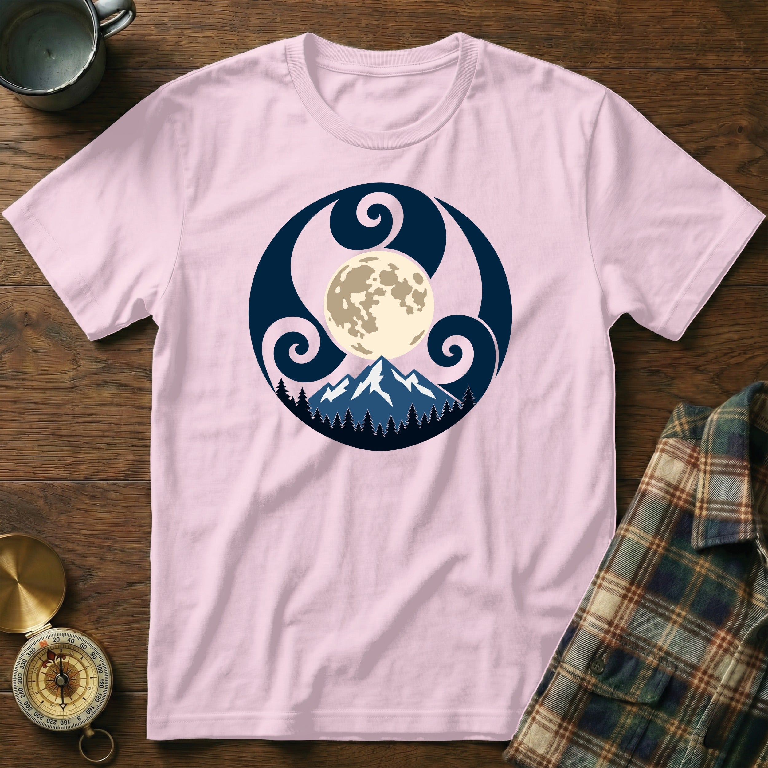 Pink t-shirt with moon, mountains, and trees graphic in dark blue circle.