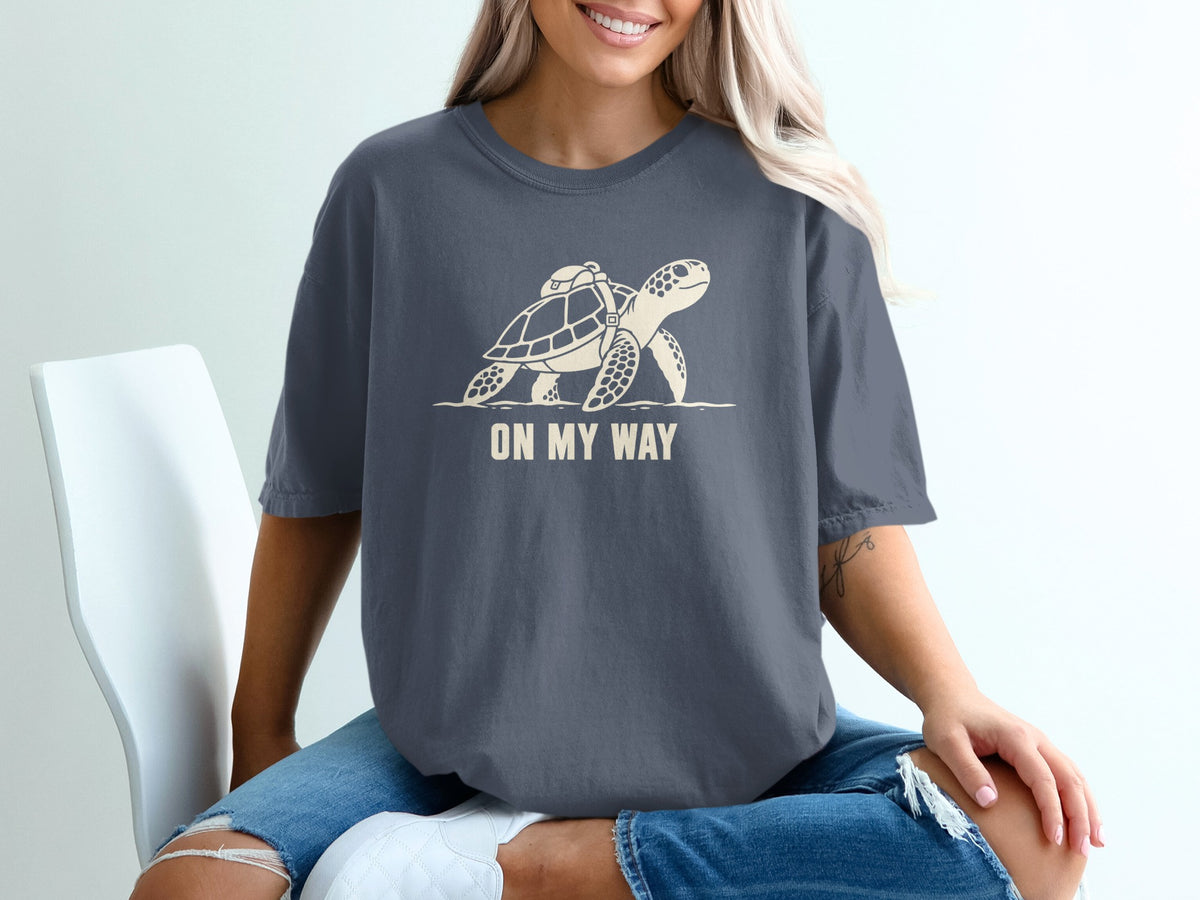 T-shirt with graphic of turtle carrying a backpack and text "ON MY WAY".