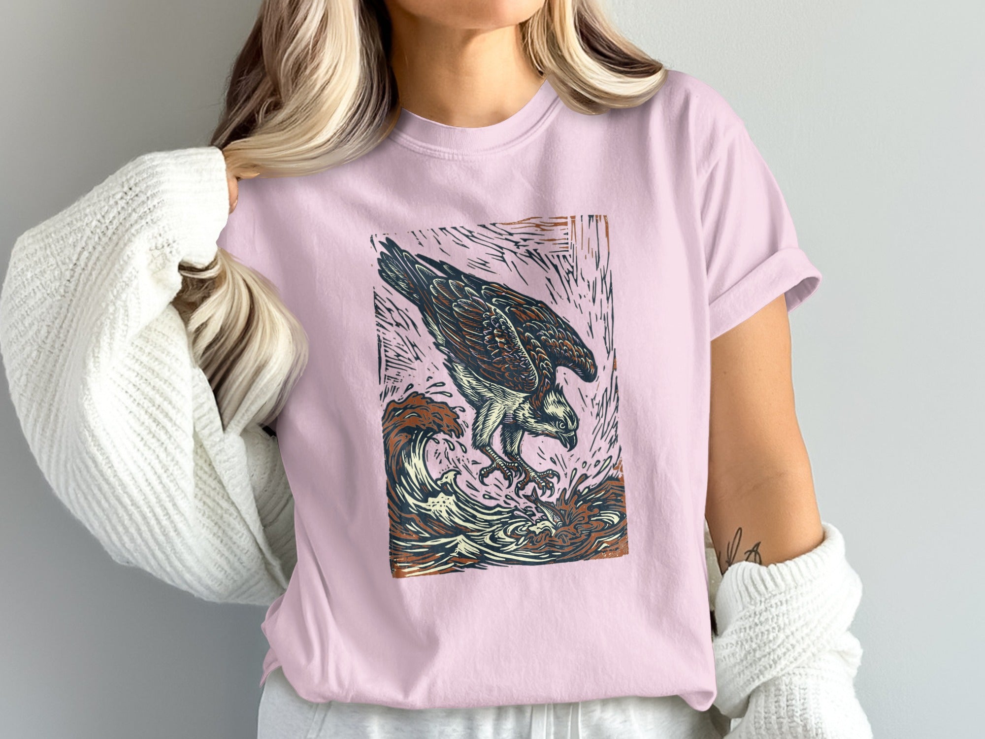 Pink t-shirt with graphic of an osprey diving into ocean waves.