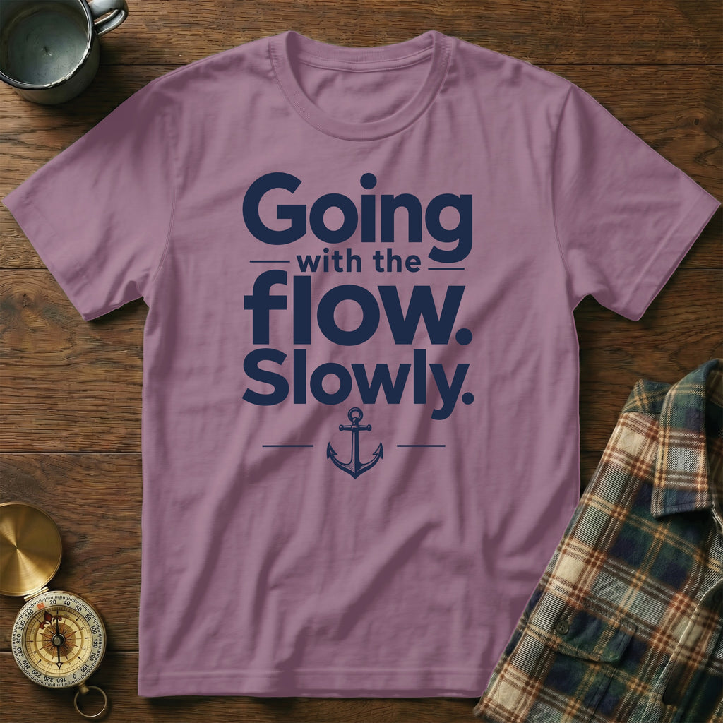 A purple crewneck t-shirt featuring the navy text Going with the flow. Slowly. and an anchor graphic.