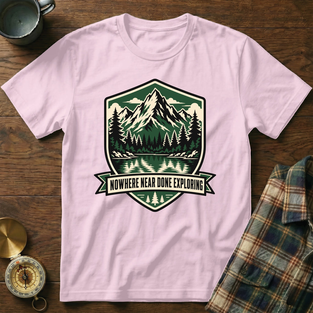 Pink t-shirt with mountain and lake graphic and text "Nowhere Near Done Exploring".