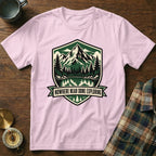 Pink t-shirt with mountain and lake graphic and text "Nowhere Near Done Exploring".