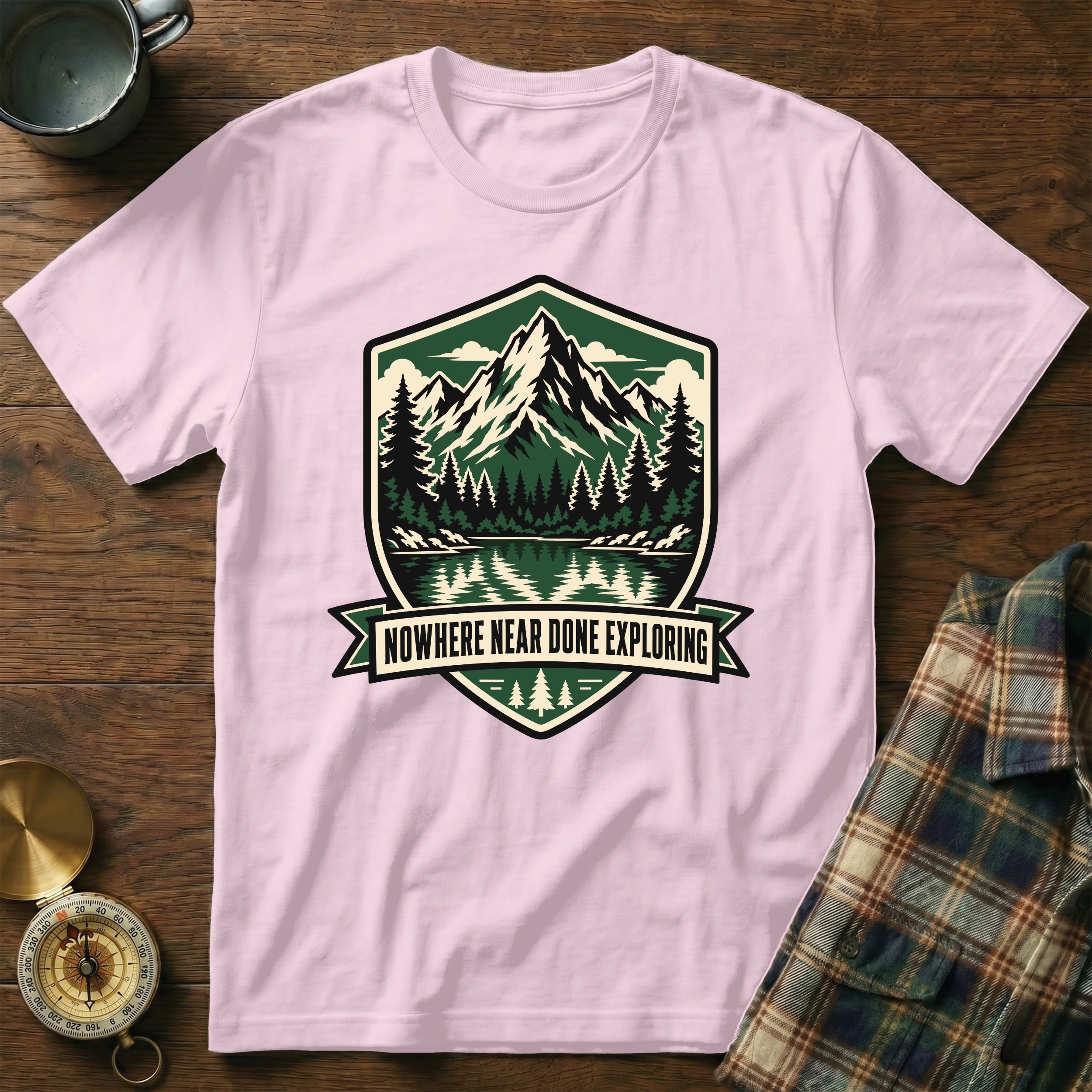 Pink t-shirt with mountain and lake graphic and text "Nowhere Near Done Exploring".