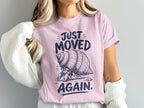 Hermit crab on pink t-shirt with text "JUST MOVED AGAIN."