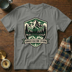 Grey t-shirt with shield graphic of mountains, lake, forest, and text "NOWHERE NEAR DONE EXPLORING".